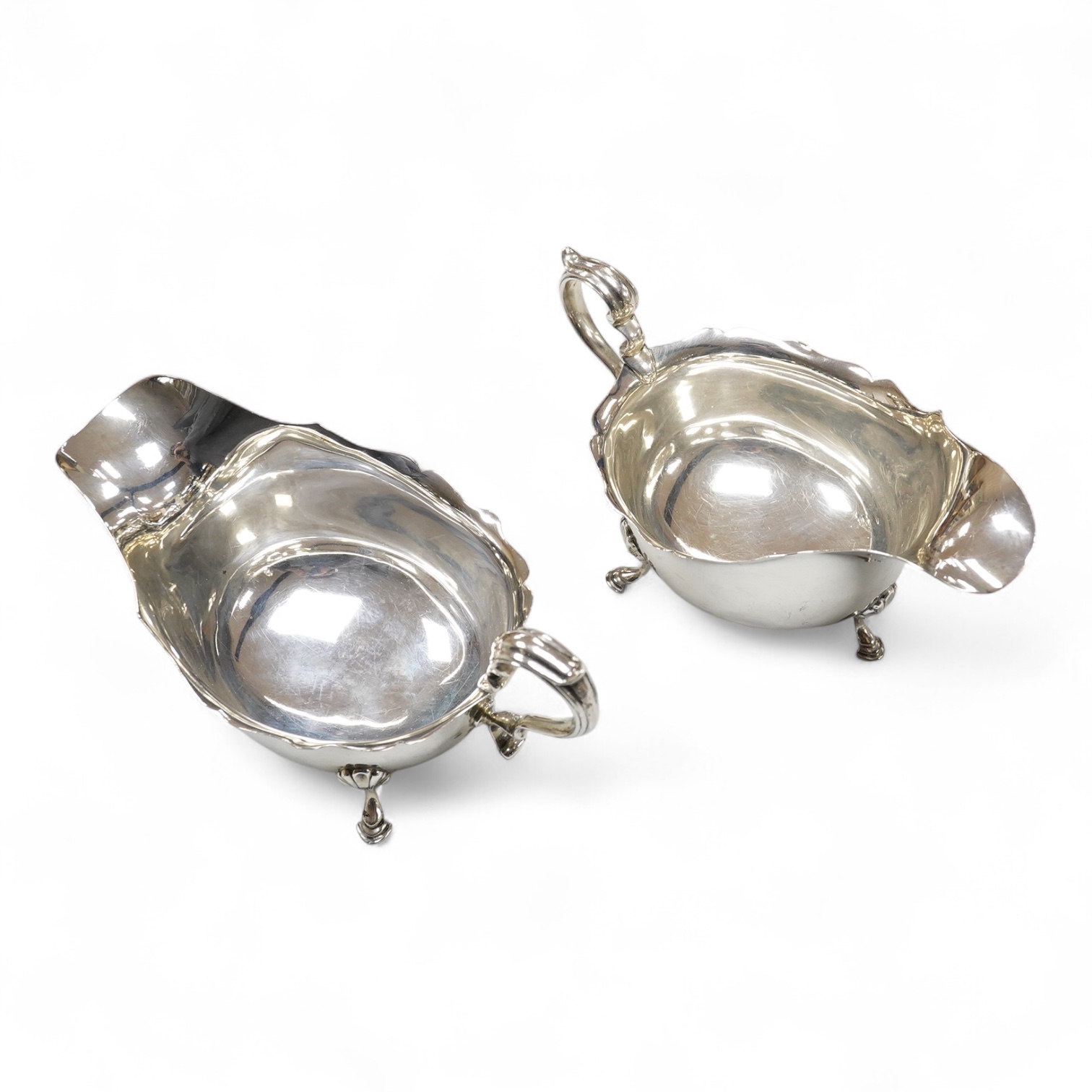 A pair of George V silver sauceboats, with scroll handles, on three hoof feet, E S Barnsley & Co, Birmingham, 1921, length approx. 17.3cm, 10.2oz.